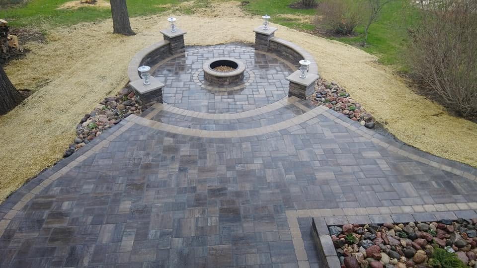 Aerial view of circular paver patio with fire pit, stone pillars, and seating wall, Platteville WI