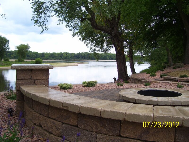 Curved stone retaining wall with fire pit overlooking a lake